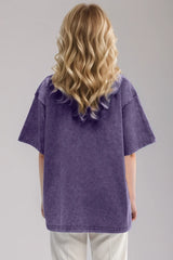 Woman wearing an oversized mauve Basic Bae round-neck half-sleeve T-shirt styled with dark denim jeans and a long pendant necklace for a relaxed, casual look.