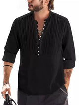 Man wearing a black button-detail long sleeve cotton polo with rolled sleeves and black pants.