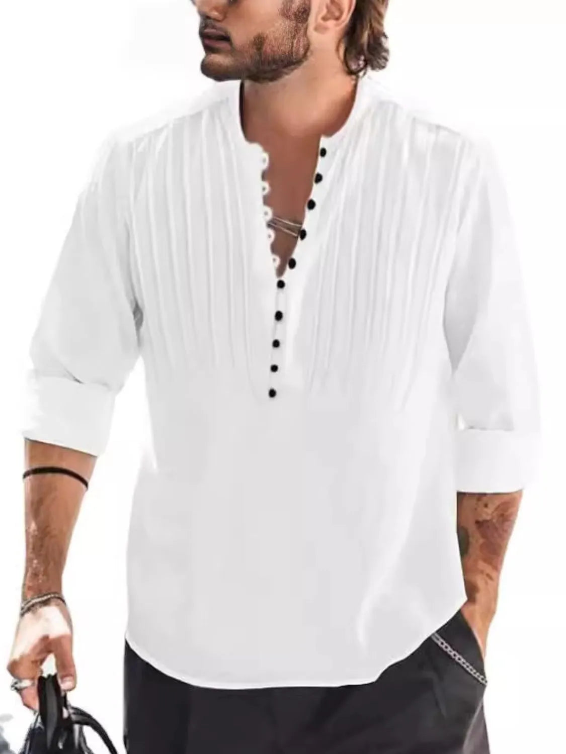 Man wearing a white button-detail long sleeve cotton polo with rolled sleeves and black pants.