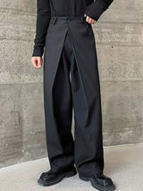 Men's black wide leg pleated pants with a button-front waistband and relaxed, full-length silhouette, styled with a black top and chunky black shoes.