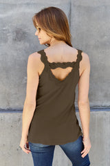 Woman wearing a mocha-colored Basic Bae lace-detail V-neck cami with delicate lace trim and cutout accents, styled with dark-wash jeans for a chic casual look.
