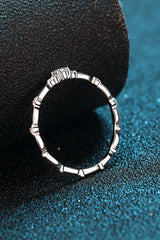 Rhodium-plated 925 sterling silver minimalist ring featuring a 0.1 carat round moissanite center stone with delicate sparkling accents on a teal background.