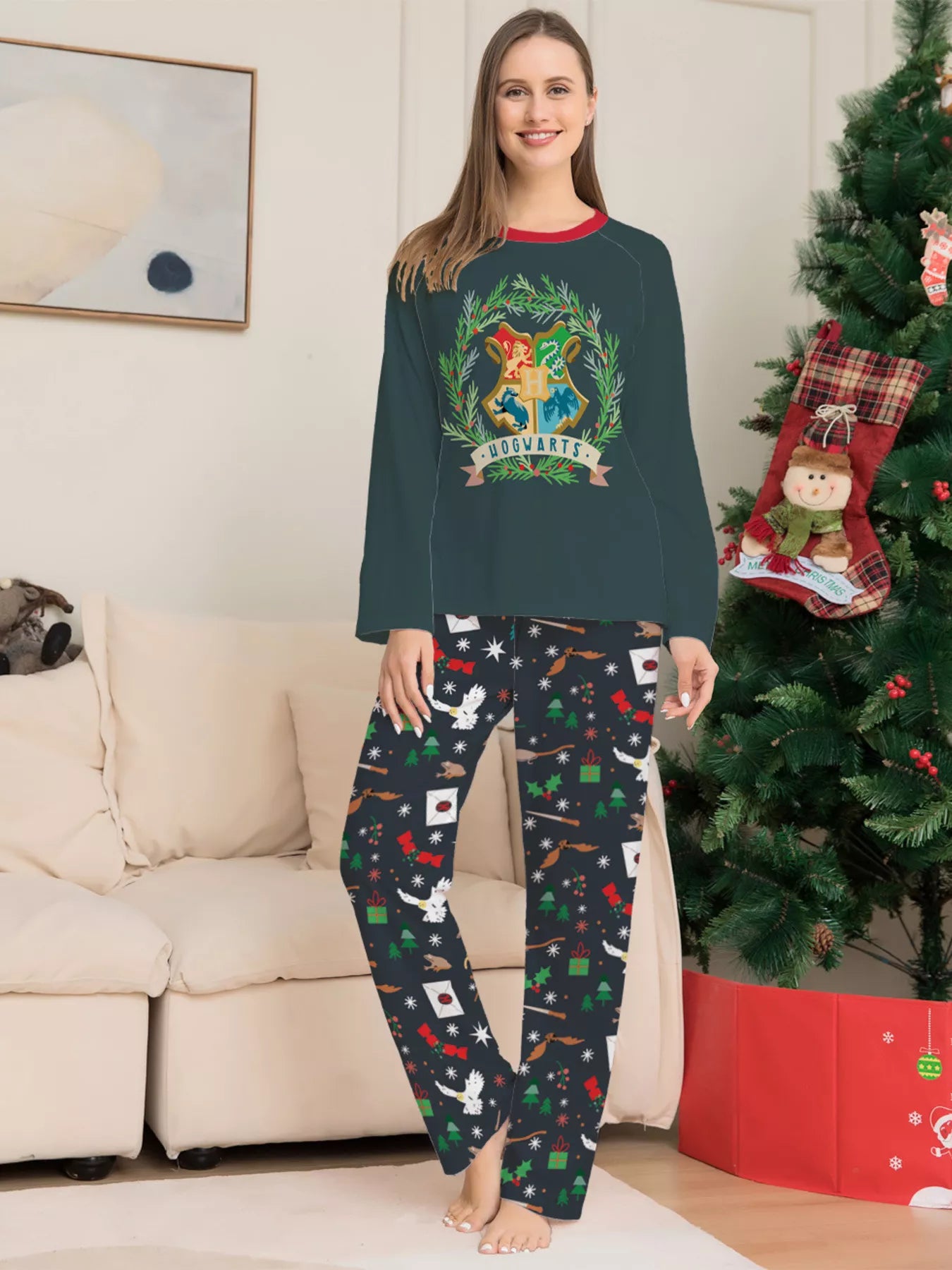 Family wearing matching dark green Hogwarts graphic Christmas pajama tops with coordinating navy holiday print pajama pants.