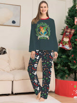 Family wearing matching dark green Hogwarts graphic Christmas pajama tops with coordinating navy holiday print pajama pants.