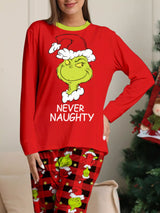 Woman modeling matching red Grinch-themed Christmas pajamas with festive graphic tops and red and black character-print pants.