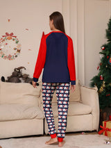 Mom wearing matching Christmas pajamas with navy tops, red raglan sleeves, festive Christmas tree lettering, and coordinating printed pants.