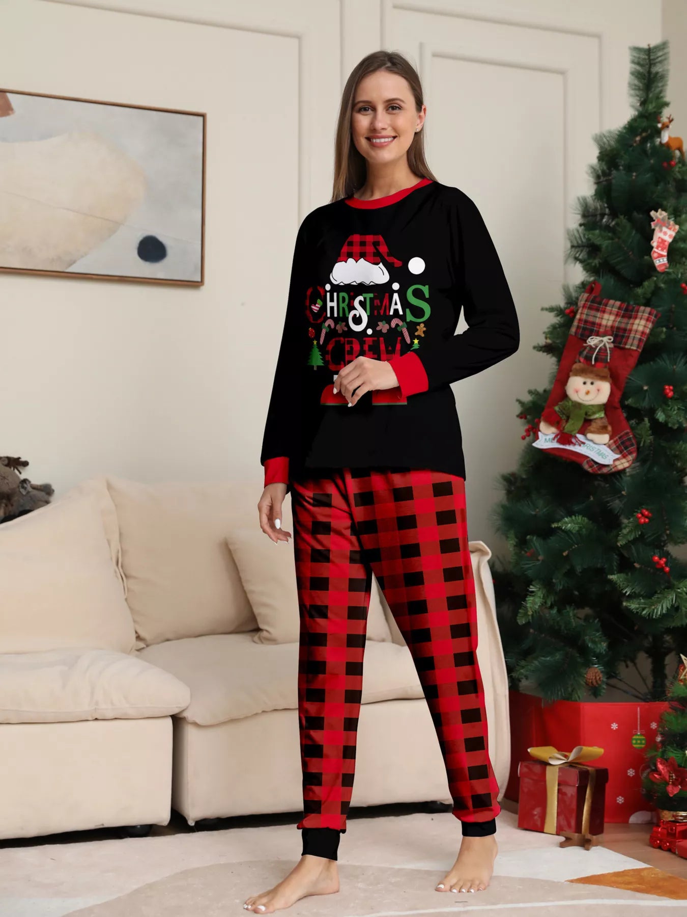 Mom modeling matching Christmas Crew pajama sets with festive black graphic tops and red and black plaid pants.