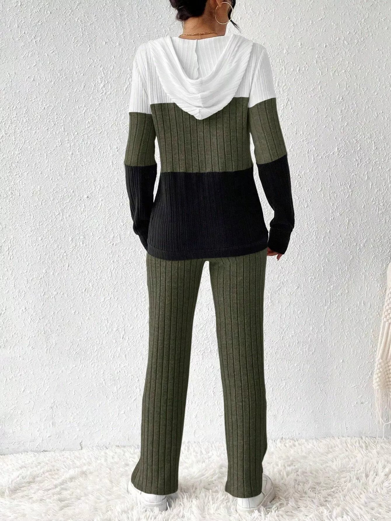 Woman wearing a moss, black and white color block half zip hooded top with matching ribbed-look pants.