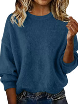 Woman wearing a navy blue round neck dropped shoulder sweater with dark-wash jeans.