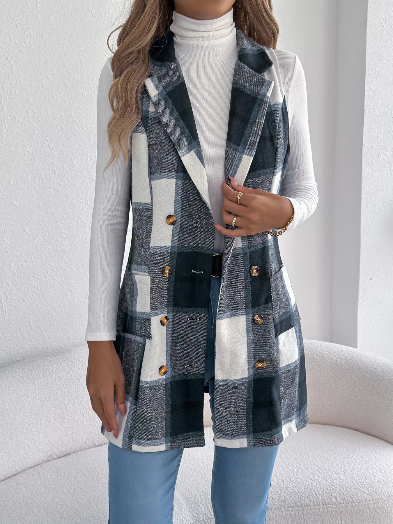 Women’s navy blue plaid double-breasted long vest coat with pockets styled over a white turtleneck and jeans.