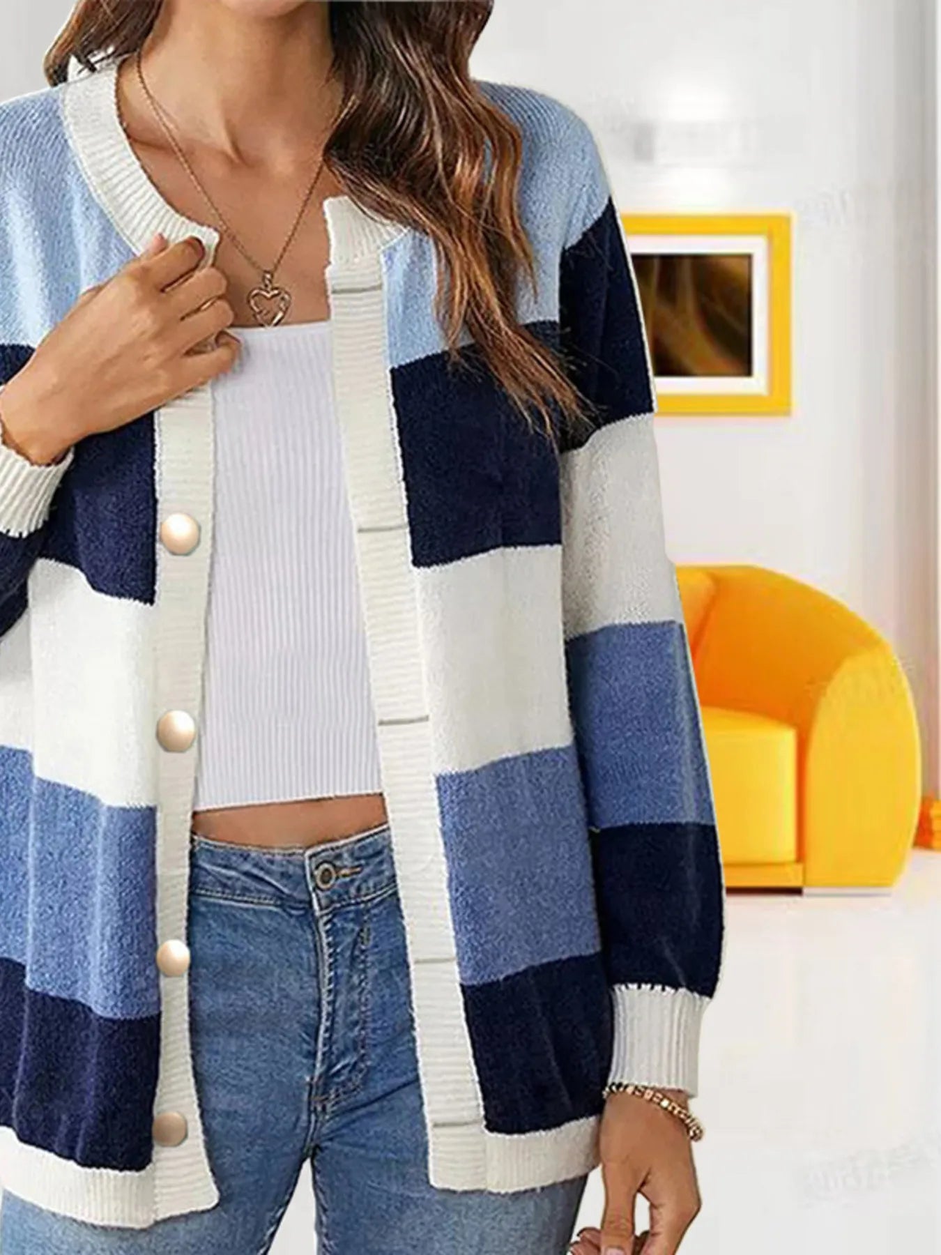 Women's navy, light blue, and cream color block knit cardigan with round neckline, button-front closure, and ribbed trim, styled with a white top and blue jeans.