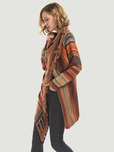 Woman wearing the Angel Wings tassel striped open-front cardigan in ochre, featuring earthy multicolor stripes, a draped asymmetrical front, and long fringe trim.