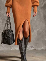 Woman wearing an ochre ribbed knit quarter-zip sweater dress with long lantern sleeves, front slit and black embroidered western boots.