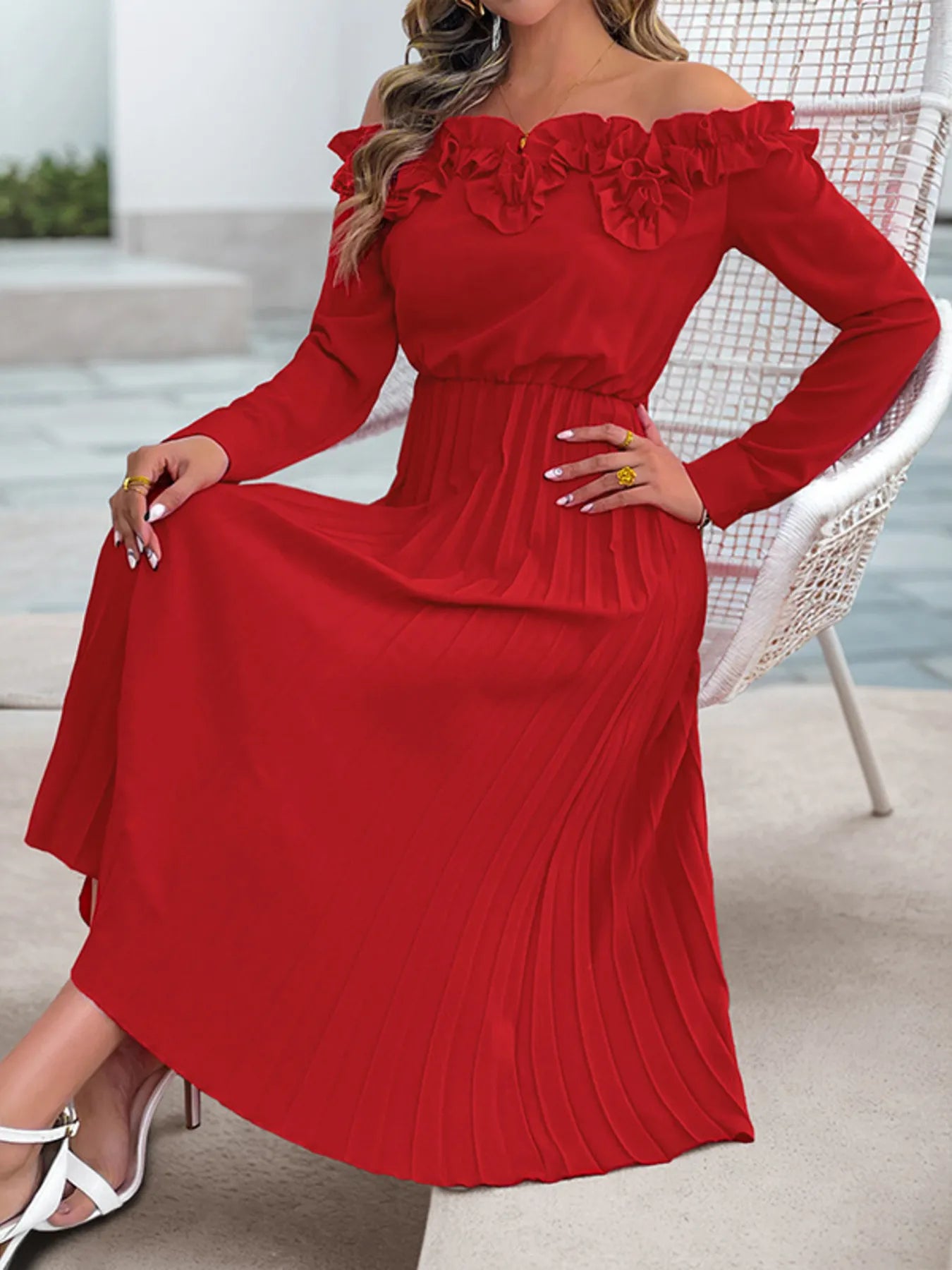 Red off-shoulder dress with floral details worn by a person sitting on a chair.