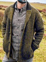 Men's olive chunky knit shawl collar cardigan with button-front closure, ribbed texture, and front pockets, layered over a gray button-down shirt.