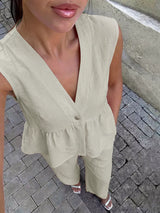 Woman wearing a light green sleeveless top and pants on a paved street.