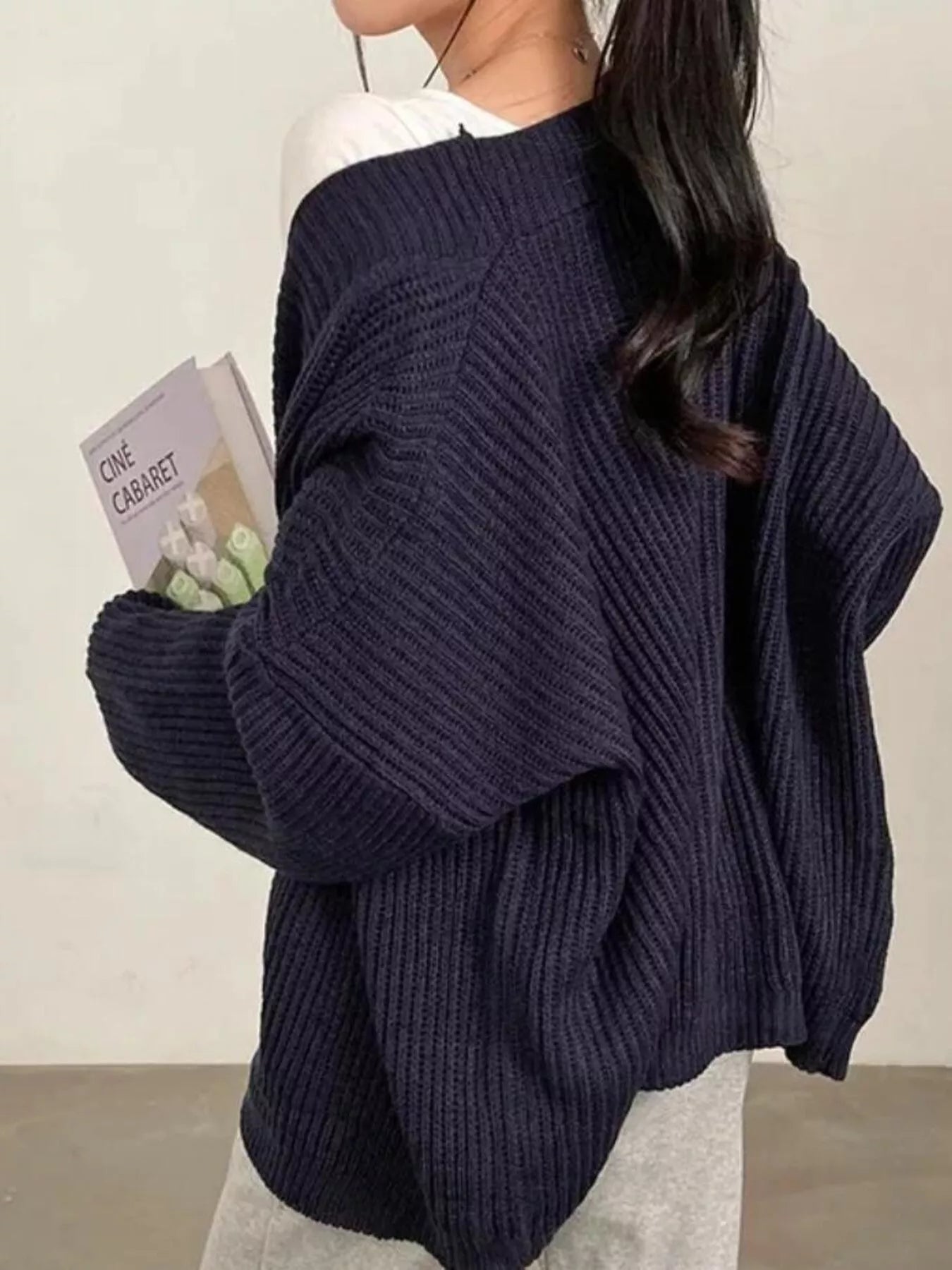 Women's black open front oversized ribbed knit cardigan layered over a white tank top with black pants, cozy fall sweater for casual everyday style.