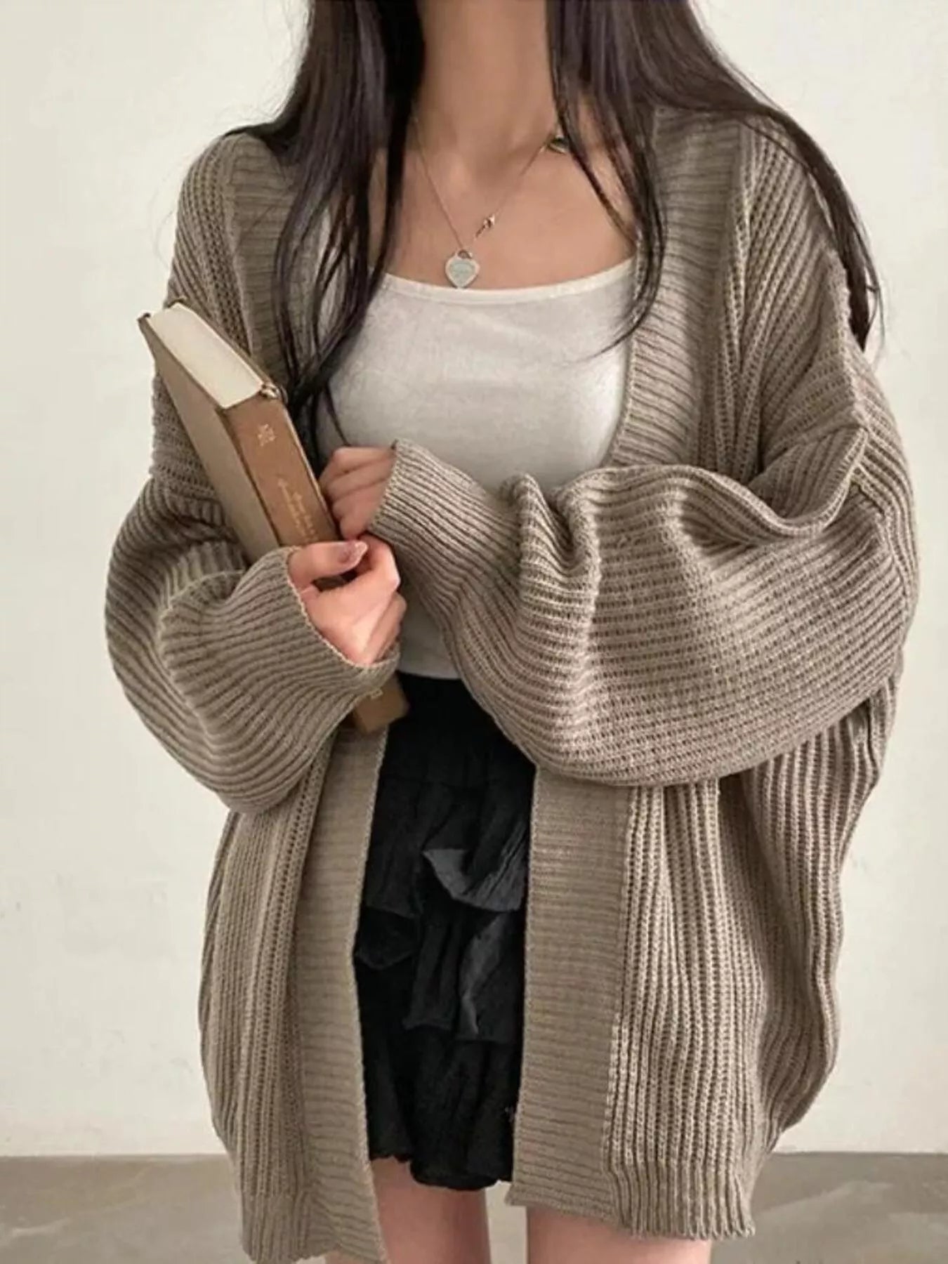 Women's khaki open front oversized ribbed knit cardigan layered over a white tank top with black pants, cozy fall sweater for casual everyday style.