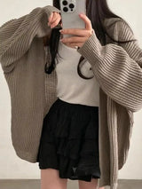 Women's khaki open front oversized ribbed knit cardigan layered over a white tank top with black pants, cozy fall sweater for casual everyday style.