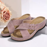 Pair of pink sandals on a white surface with a blurred floral background