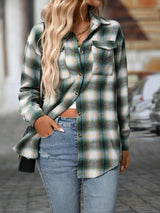 Woman wearing a deep green plaid oversized button-up shirt layered over a white top with jeans and brown crossbody bag.