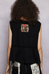 Person wearing a black sleeveless top with a colorful pocket on a gray background