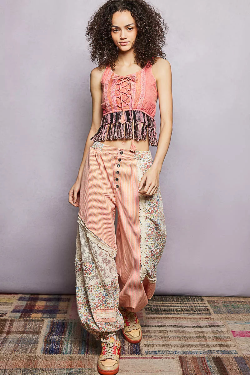 Woman wearing a pink top and floral pants on a plain background