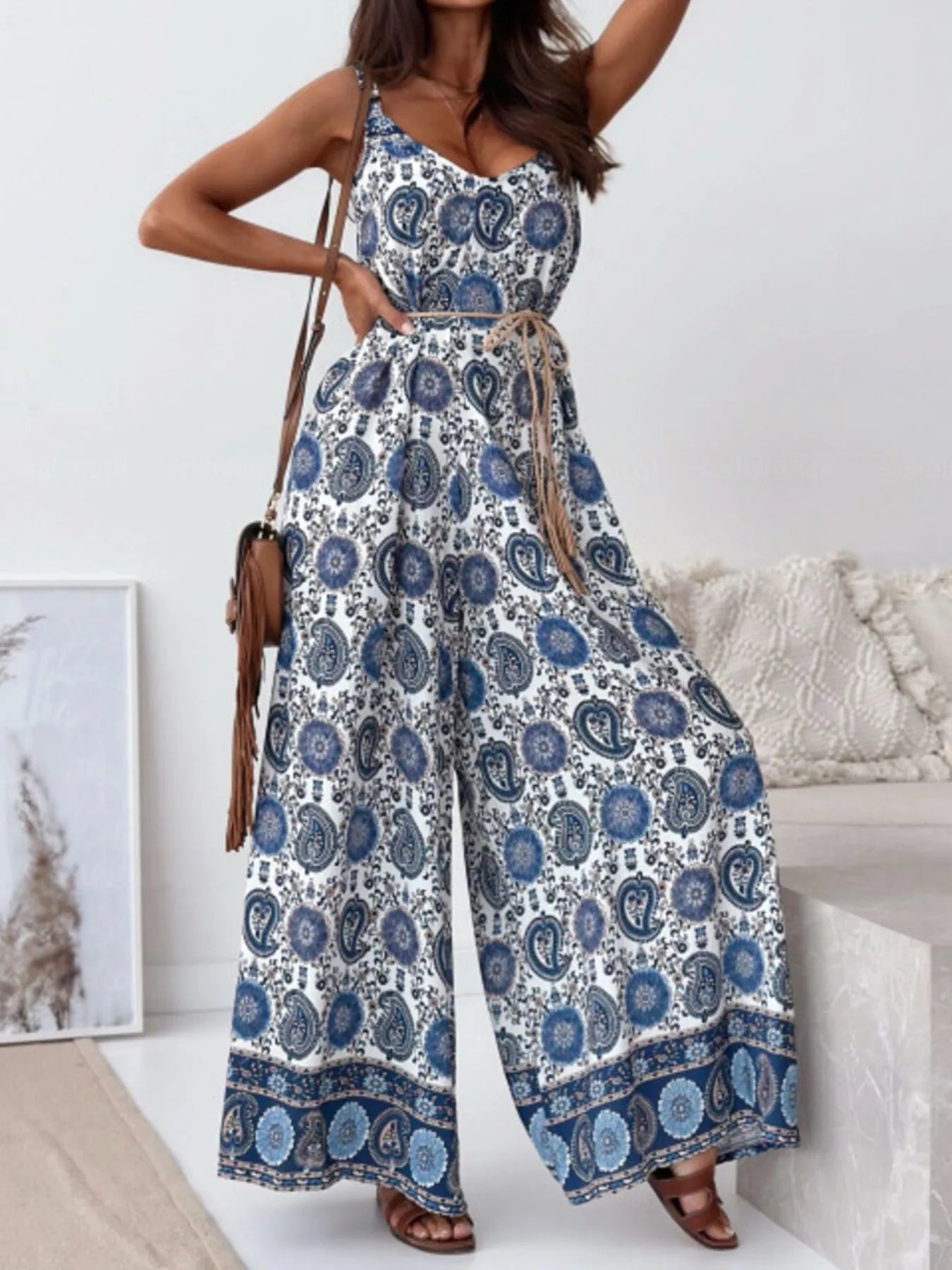 Woman wearing a blue and white patterned jumpsuit in a room with a couch and decor.