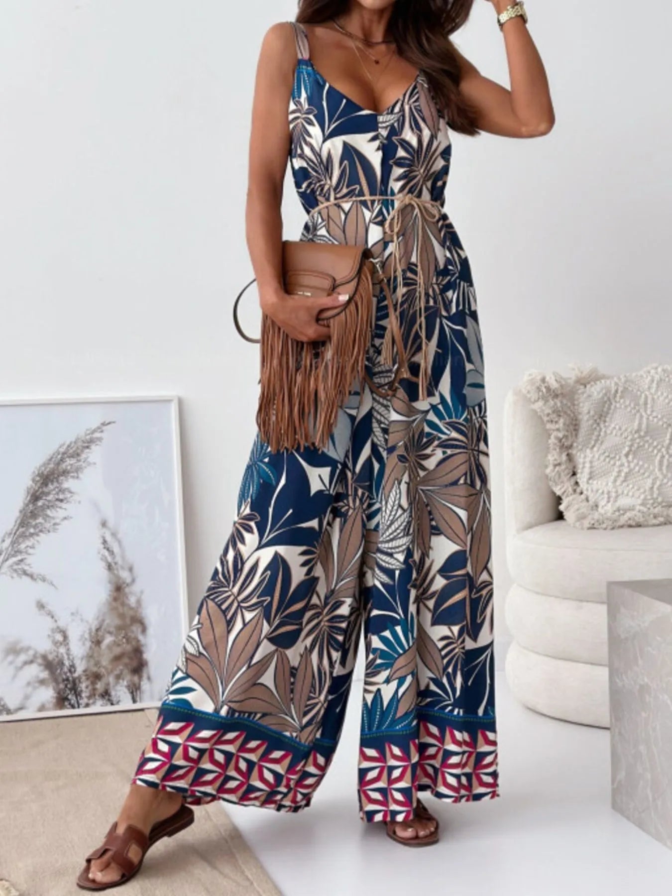 Woman wearing a colorful big leaf-patterned jumpsuit in a minimalistic room.