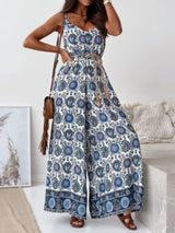 Woman wearing a blue and white feathered patterned jumpsuit in a minimal indoor setting.