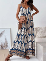 Woman wearing a blue and white patterned jumpsuit holding a brown handbag indoors.