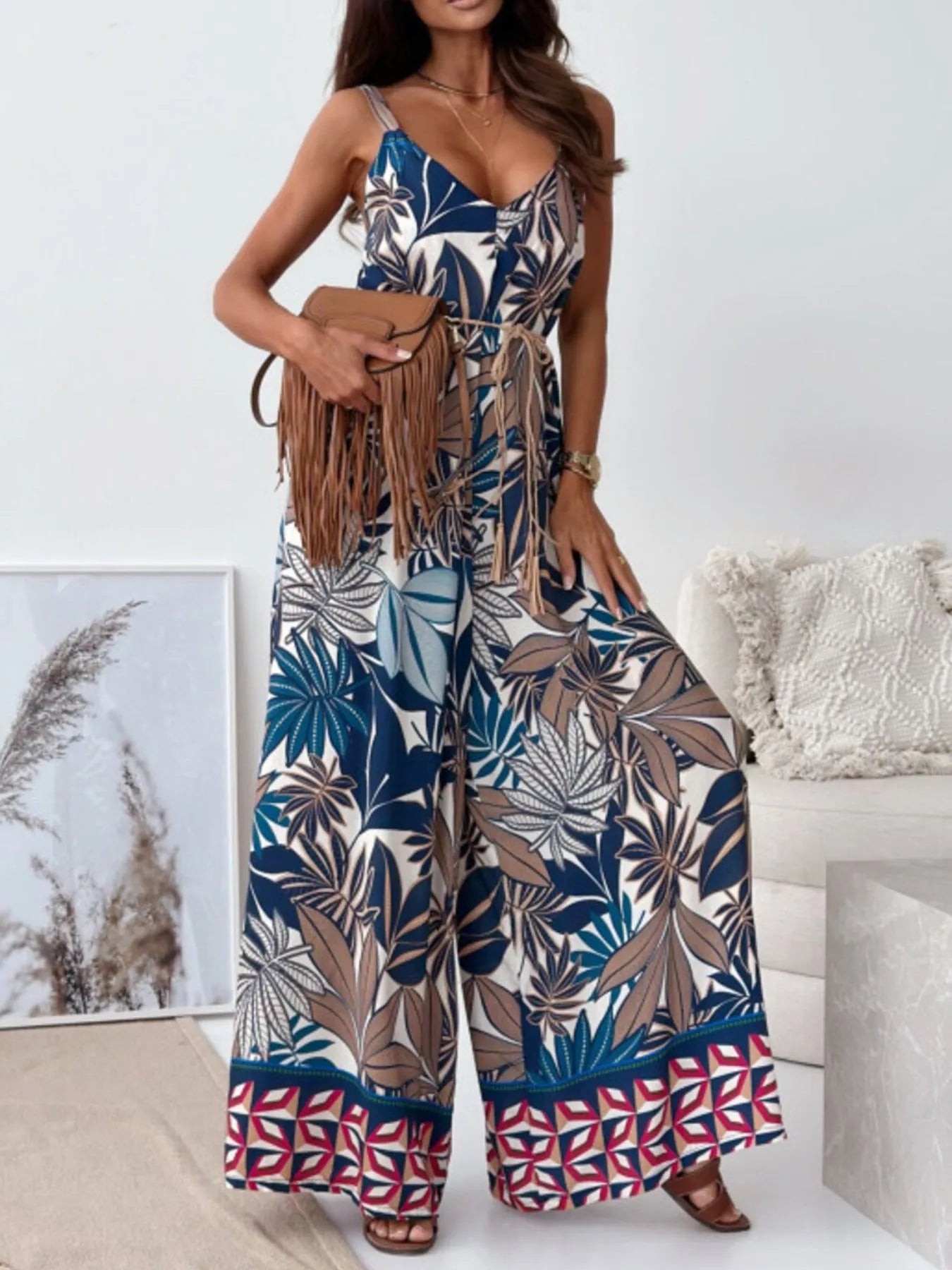 Woman wearing a big leaves colorful patterned jumpsuit in a living room setting.