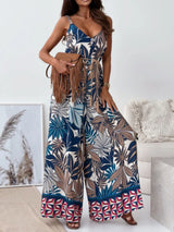 Woman wearing a big leaves colorful patterned jumpsuit in a living room setting.