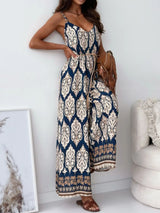 Woman wearing a blue and white patterned jumpsuit in a room with a white wall and chair.