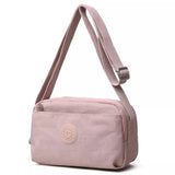 Small pink nylon crossbody bag with an adjustable matching strap, silver-tone buckle, zippered top closure, and front pocket detail.