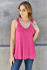 Woman wearing a pink colored Basic Bae lace-detail V-neck cami with delicate lace trim and cutout accents, styled with dark-wash jeans for a chic casual look.