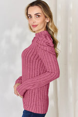 Woman wearing a pink Basic Bae ribbed mock neck long sleeve top with ruched puff shoulders, paired with dark blue jeans.