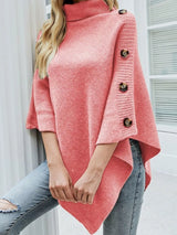 Women's pink knit turtleneck poncho pullover with button accents and flowing poncho silhouette.