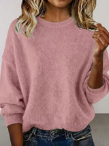Woman wearing a pink round neck dropped shoulder sweater with dark-wash jeans.