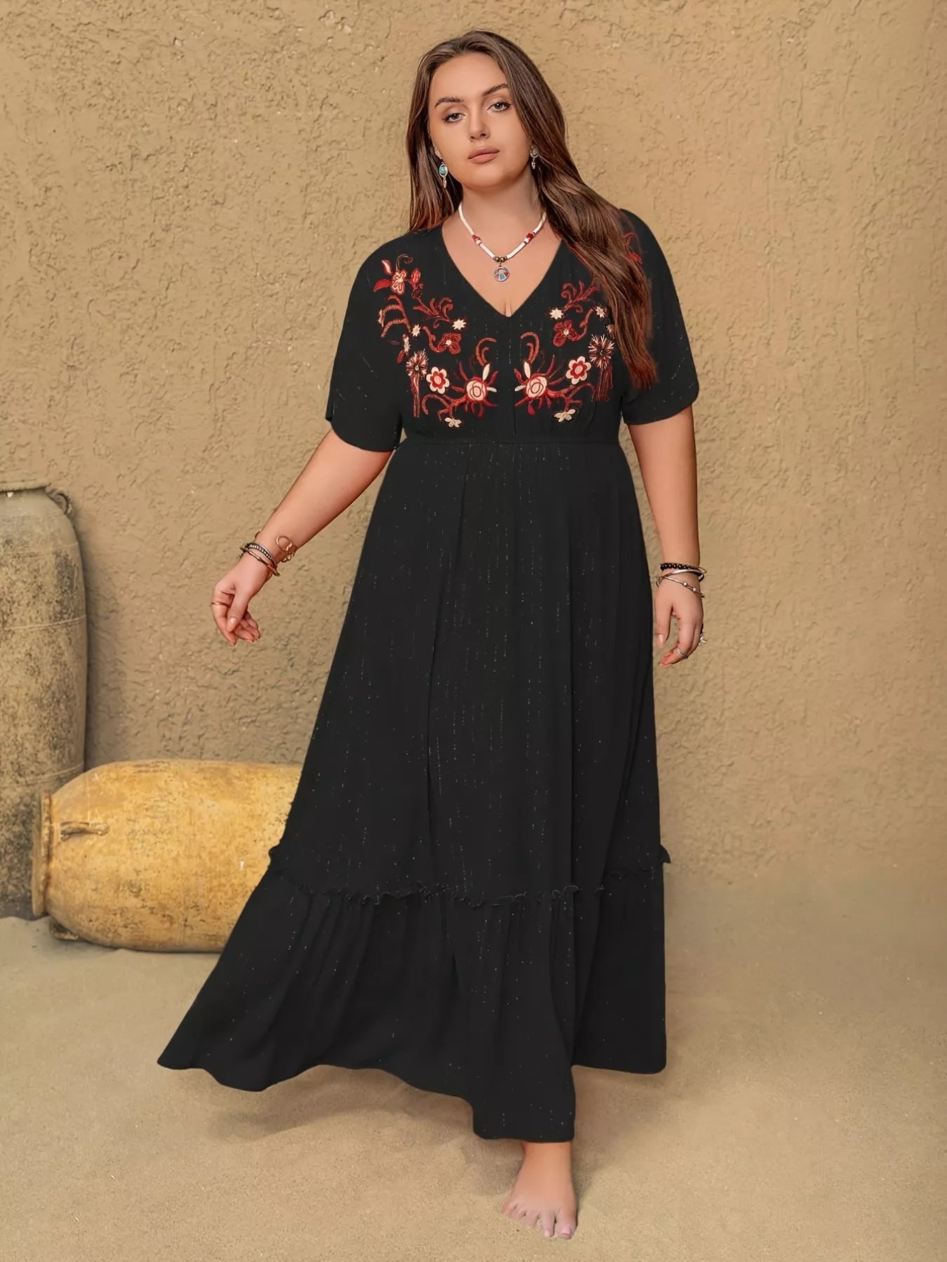 Woman wearing a black dress with floral embroidery against a beige background