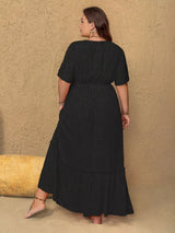 Woman wearing a black dress against a beige wall.