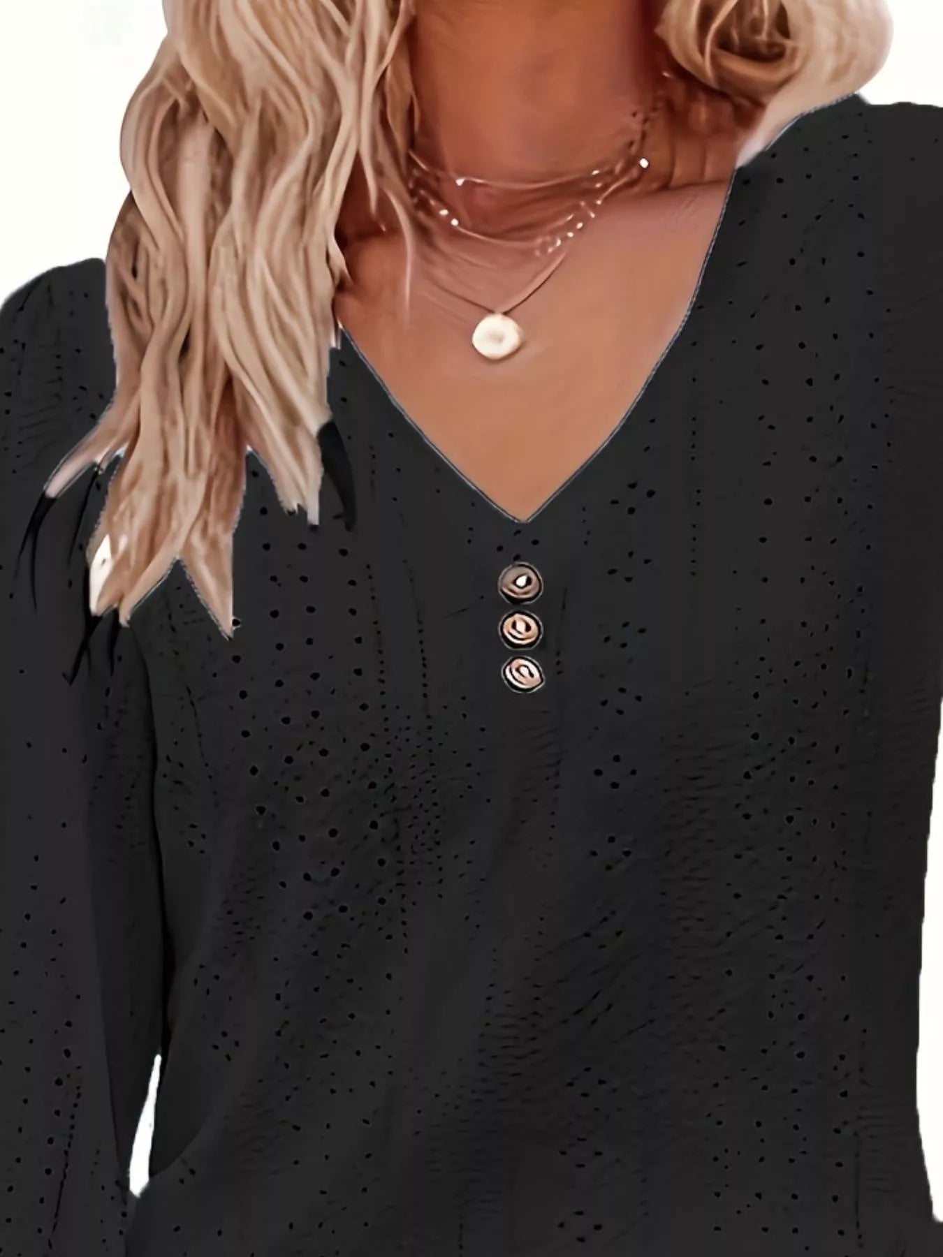 Black long-sleeve top with button details worn by a person with blonde hair.