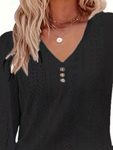 Black long-sleeve top with button details worn by a person with blonde hair.