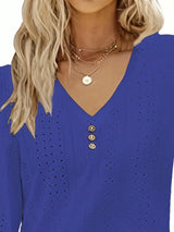Blue top with button details worn by a person with blonde hair.