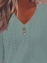 Green long-sleeve top with button details on a person.