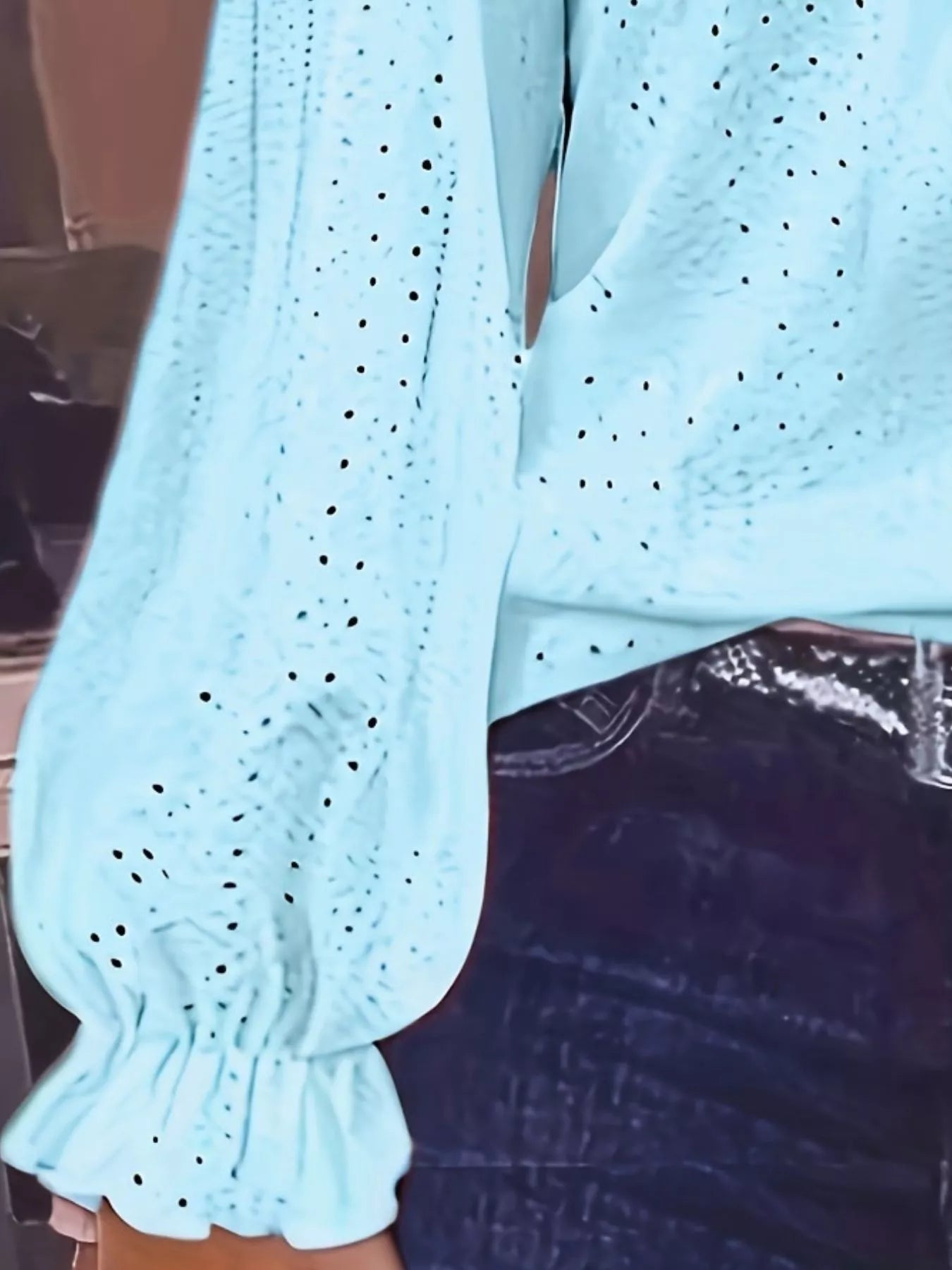 Light blue sweater with eyelet details on a dark background