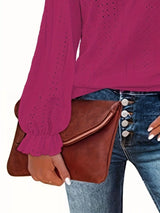 Person wearing a rose red blouse and blue jeans holding a brown leather clutch.