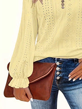 Person wearing a yellow long-sleeve top and blue jeans, holding a brown leather bag.