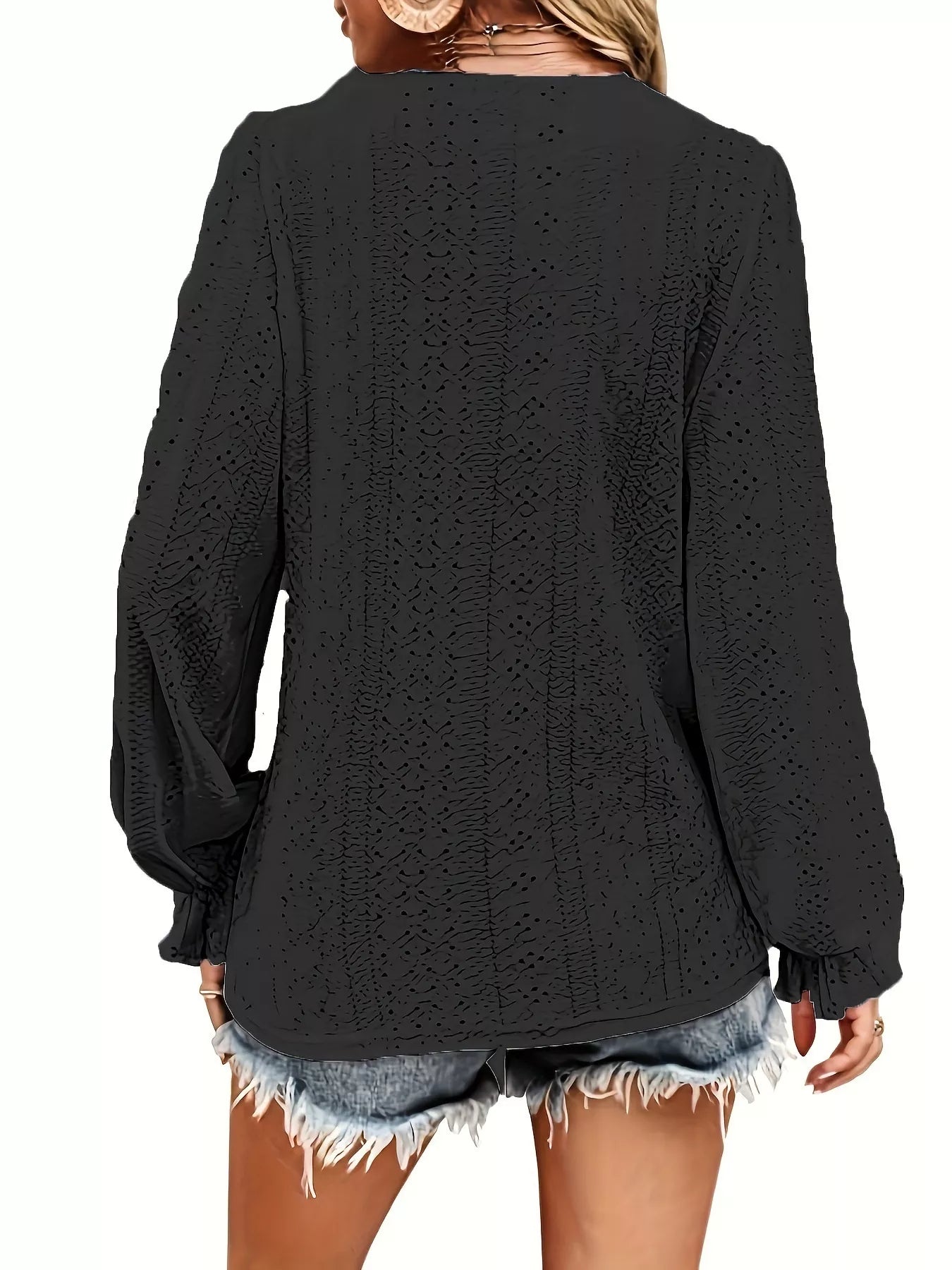 Black knitted blouse worn by a person on a white background showing back of blouse.
