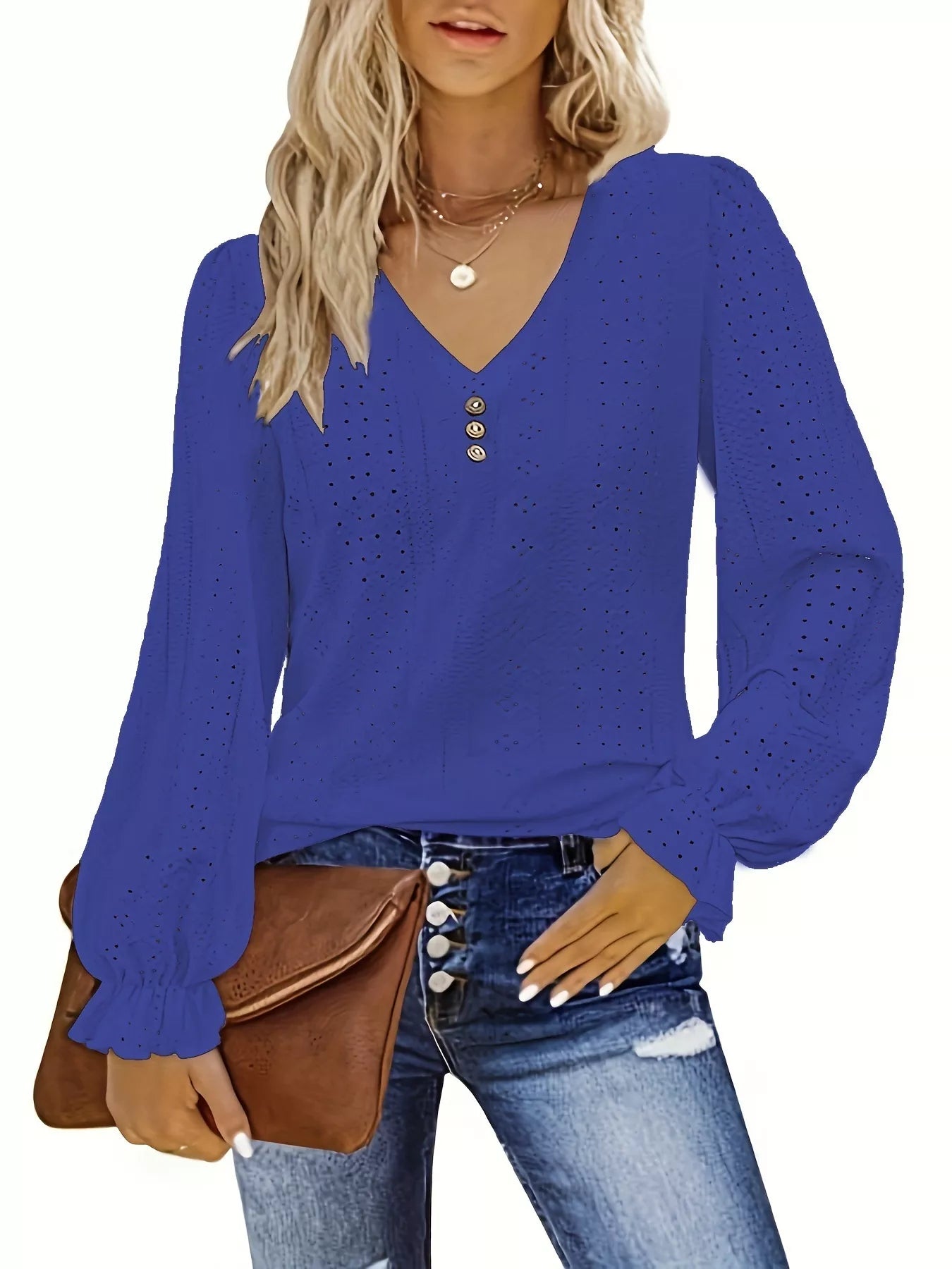 Woman wearing a blue long-sleeve top with a brown clutch on a white background